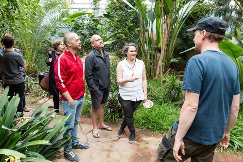 At the recently renovated “World of Birds” exhibit, a special glass roof simulates a natural living environment for the birds that live there, curator Tobias Rahde (right) explains to the fellowship recipients.