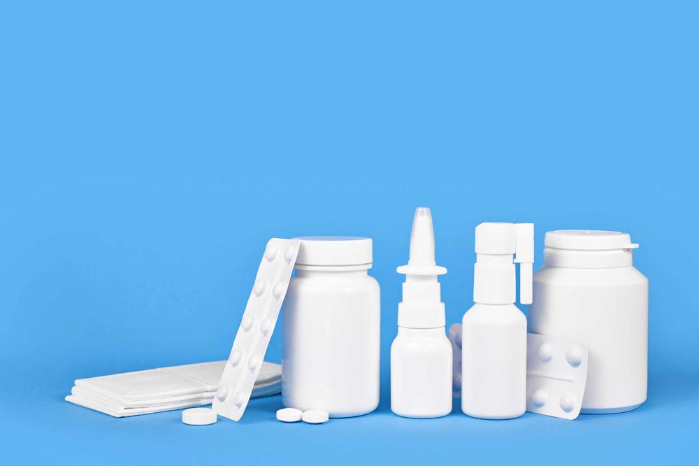 Medikamente ohne Aufdruck in verschiedenen Verpackungen vor blauem Hintergrund