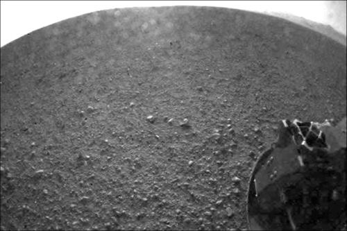 Dies ist eines der ersten Bilder, das von der NASA-Sonde "Curiosity" gesendet wurde. Es wurde mit einem sogenannten "Fisheye"-Weitwinkelobjektiv aufgenommen. Unten rechts im Bild ist ein Rad der Sonde zu sehen.