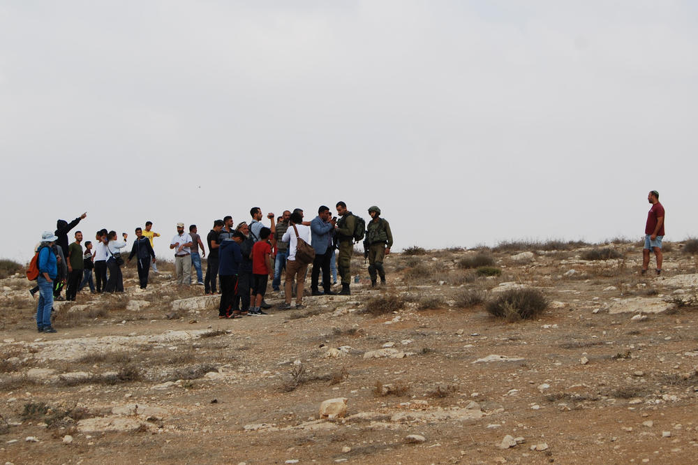 At Hill 833: A settler faces a group of Palestinians. He never lets go of the pistol he has in his right pocket. Some Palestinians are filming in order to protect themselves. Israel Defense Forces are trying to mediate.