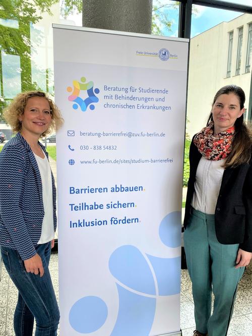 Katrin Fischer (left) und Anja Ahrens (right) standing beside a roll-up banner for advice and support services at the 2022 inFUtage