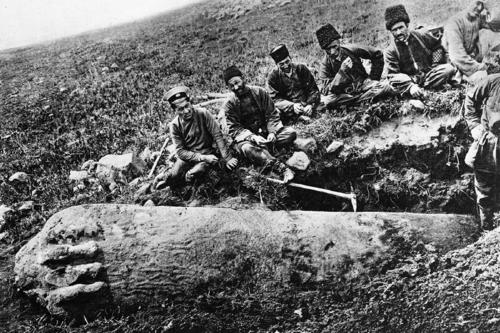 Auf diesem Foto ist eine Gruppe Einheimischer um 1909 vor einem liegenden Drachenstein zu sehen.