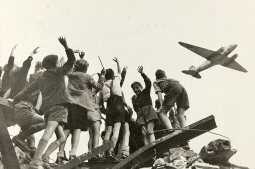 Salvation from the air: Children wave to one of the “candy bombers” in July 1948. The Berlin Airlift organized by the western Allies supplied the people of Berlin with food and essentials such as fuel during the Berlin Blockade. 