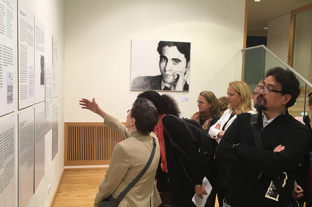 Besucherinnen und Besucher der Ausstellung lesen an der Wand angebrachte Texttafeln. Im Hintergrund hängt ein schwarz-weiß Porträt des Dichters Federico Garcia Lorca.