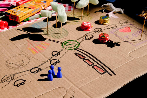 Flache Pappe mit aufgezeichneten Straßen, S-Bahn-Symbol, Spielfiguren, Stiften und weiteren Basteleien