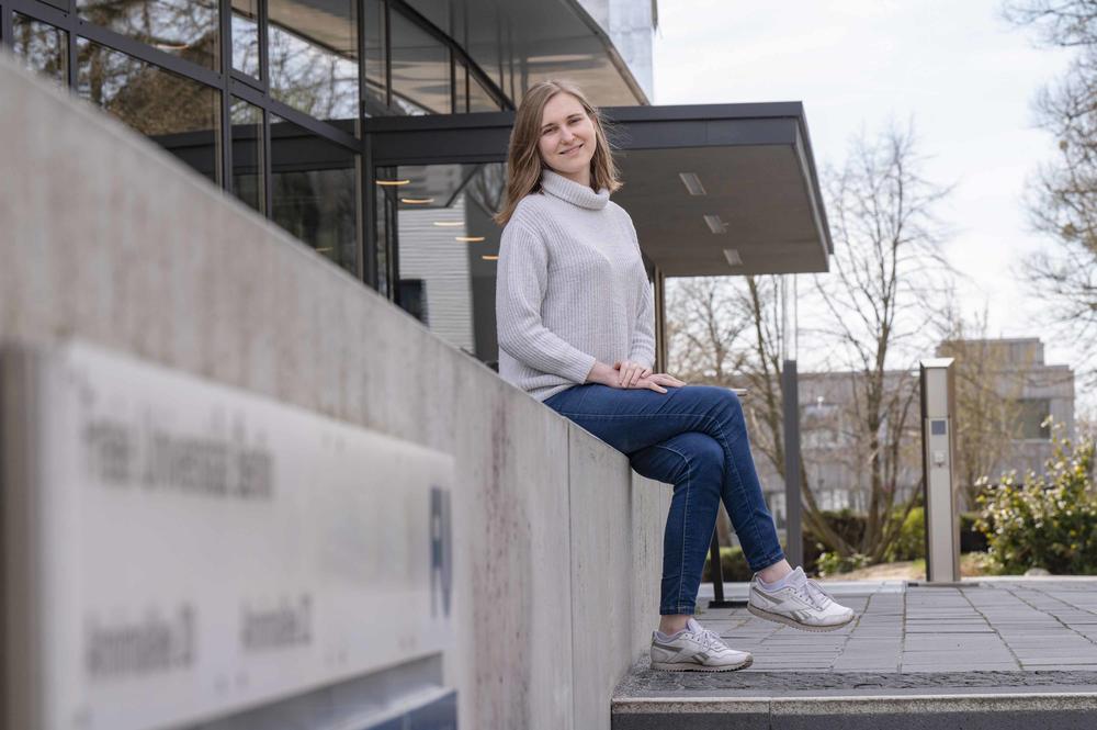 Die ukrainische Studentin Krystyna Krupko sitzt auf einer Mauer vor dem Gebäude des Instituts für Chemie und Biochemie der Freien Universität Berlin.
