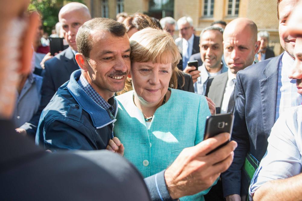 Angela Merkel lässt im September 2015 mit dem Geflüchteten Shaker Kedida aus Mossul ein Selfie machen, im Hintergrund eine Menschenmenge