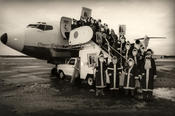 Heinzelmännchen der Freien Universität als Weihnachtsmänner beim Verlassen eines Flugzeugs auf dem Flughafen Tempelhof.