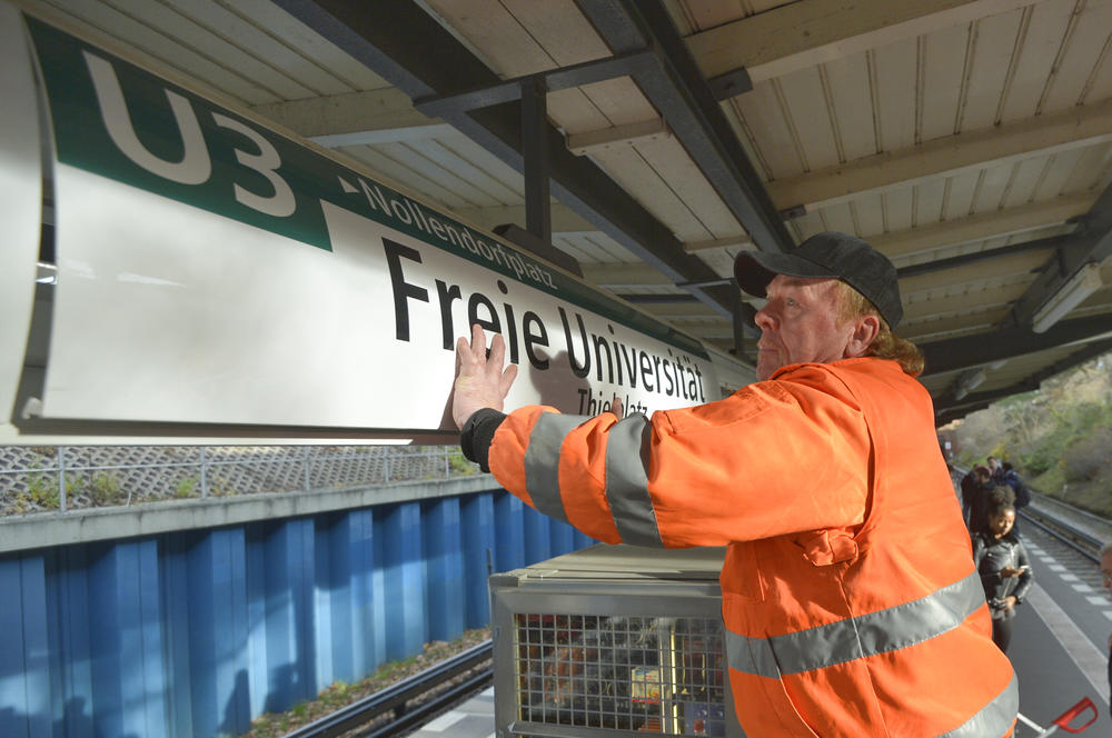 BVG-Mitarbeiter Wolfgang Murzoch bringt das neue Stationsschild an, und damit hat die Freie Universität knapp 68 Jahre nach ihrer Gründung eine eigene U-Bahnhaltestelle.