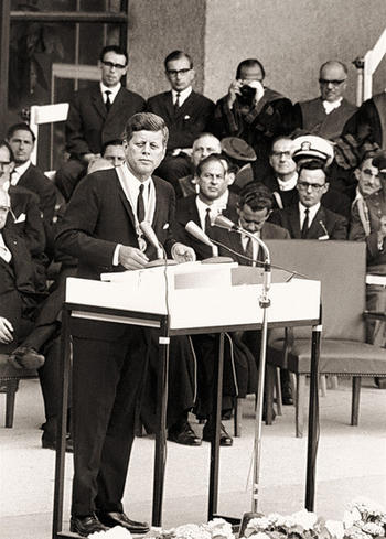 John F. Kennedy steht am Rednerpult auf der Tribüne vor dem Henry-Ford-Bau